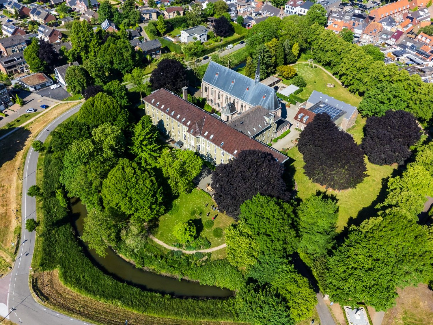 Luchtfoto van het Dominicanenklooster in Huissen, de locatie van De School voor Transitie, omringd door groen en rustgevende natuur.